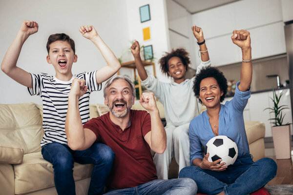Excited family football fans watching sport tv game celebrating goal together