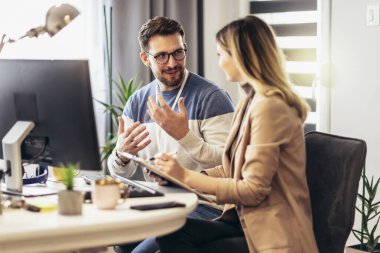 Genç çift evdeki masada otururken bir proje üzerinde çalışıyor.