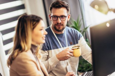 Genç çift evdeki masada otururken bir proje üzerinde çalışıyor.
