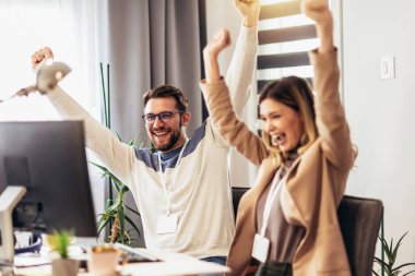 Young caucasian couple working using computer laptop at home celebrating victory with happy smile and winner expression with raised hands