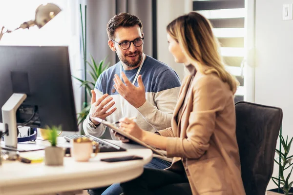 Genç çift evdeki masada otururken bir proje üzerinde çalışıyor.