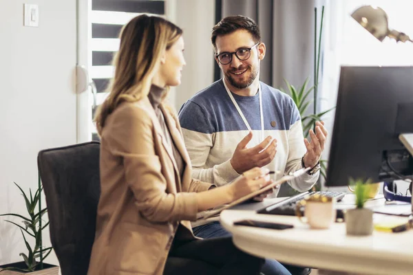 Genç çift evdeki masada otururken bir proje üzerinde çalışıyor.