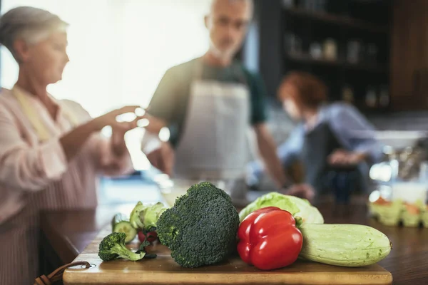 Grupo Amigos Seniores Jantar Casa Cozinhar Foco Vegetais — Fotografia de Stock