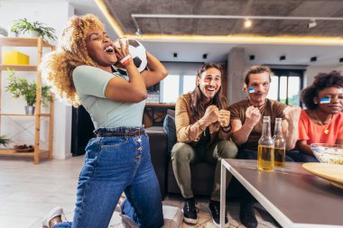 Genç bir grup televizyonda spor izliyor ve tezahürat yapıyor. Duygusal futbol hayranları evde futbol maçı izliyorlar. Boyalı Yüzlü Spor Hayranları TV 'de Kanepe İzleme Oyunu' nda oturuyor