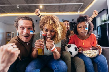 Genç bir grup televizyonda spor izliyor ve tezahürat yapıyor. Duygusal futbol hayranları evde futbol maçı izliyorlar. Boyalı Yüzlü Spor Hayranları TV 'de Kanepe İzleme Oyunu' nda oturuyor