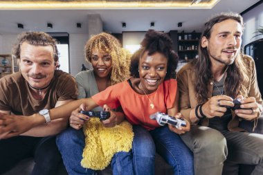 Group of friends playing video games. Happy fellows having fun at home with joysticks playing video games, gesturing and screaming, enjoying time together.