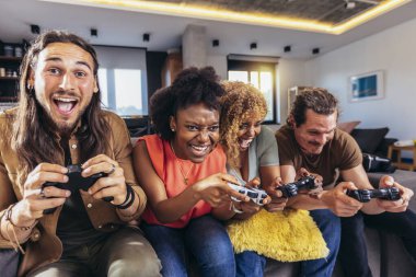 Group of friends playing video games. Happy fellows having fun at home with joysticks playing video games, gesturing and screaming, enjoying time together.