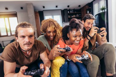 Group of friends playing video games. Happy fellows having fun at home with joysticks playing video games, gesturing and screaming, enjoying time together.