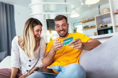 Happy couple managing home finances using digital tablet and credit card for online payment