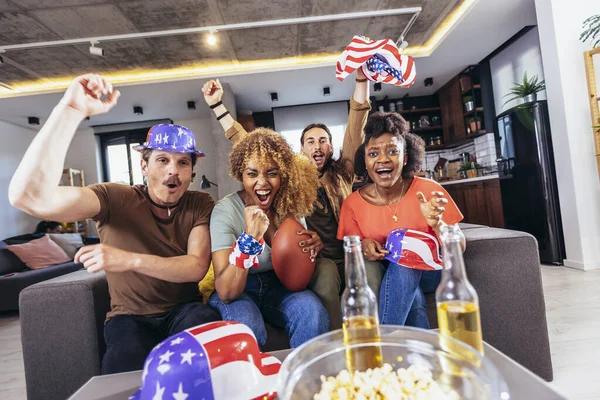 Arkadaşlar birlikte spor ligine tezahürat yapıyor. Spor hayranları TV 'de bir kanepede oturuyorlar.