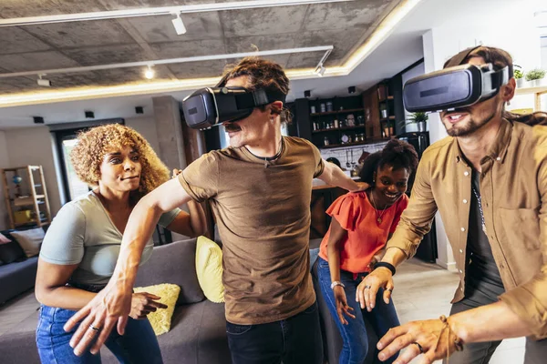 Neşeli arkadaşlar evde VR ile eğleniyorlar.