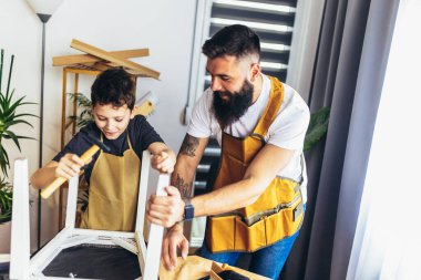 Neşeli genç erkek marangoz ve oğlu atölyede çalışıyor.