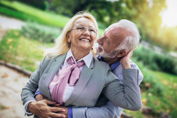 Senior active caucasian couple hugging looks happy in the park in the afternoon