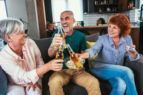Skupina Seniorů Popcornem Pivem Sledující Spolu Víkendu Doma Televizi — Stock fotografie