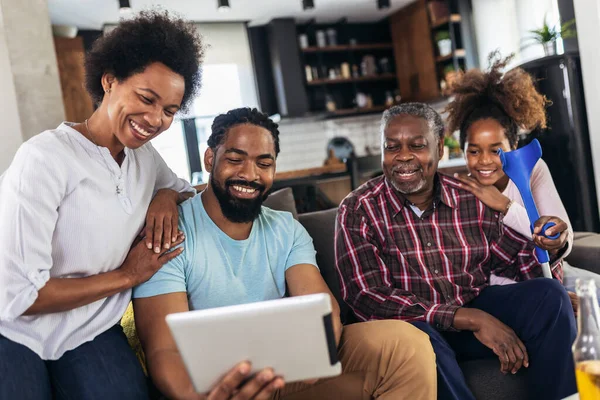 Portrait of multi generation family sitting in living room and using tablet pc