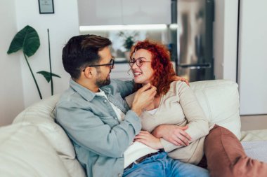 Genç mutlu çift evde komik bir şeyler anlatırken eğleniyor.