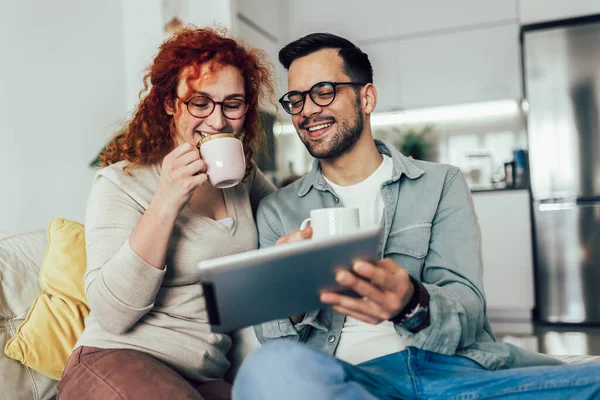 Pareja Joven Viendo Contenido Multimedia Línea Una Tableta Sentada Sofá —  Fotos de Stock