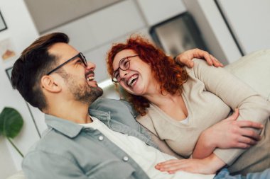 Genç mutlu çift evde komik bir şeyler anlatırken eğleniyor.