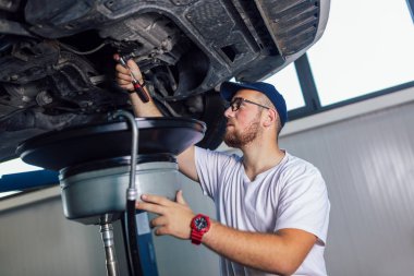 Garajında araba tamir eden bir tamircinin portresi, yağ değişimi..