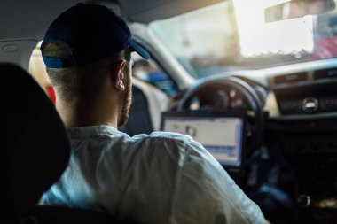 Profesyonel araba tamircisi dizüstü bilgisayar kullanarak oto tamir servisinde çalışıyor..