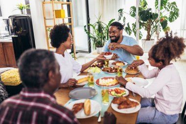 Yemek masasında yemek yiyen çok nesilli Afro-Amerikan bir aile..