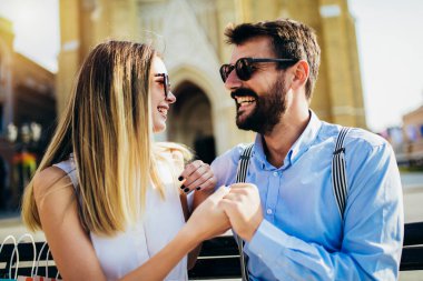 Güzel, genç bir çift bankta oturuyor, sarılıyor ve eğleniyorlar.