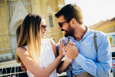 Güzel, genç bir çift bankta oturuyor, sarılıyor ve eğleniyorlar.