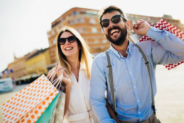 Alışveriş torbalarıyla mutlu bir çiftin portresi. İnsanlar, satış, tüketim ve yaşam tarzı konsepti..