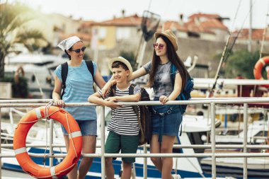 Happy mother, son and daughter walking together at seaside with luggage backpack. Travel, tourism,  family concept.