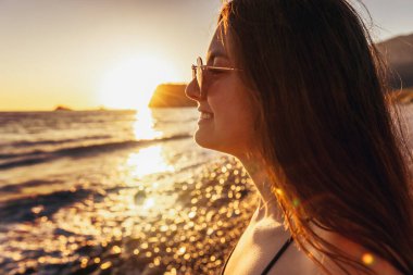 Genç kız deniz manzarası ve gün batımının tadını çıkarıyor. Seyahat, tatil kavramı.