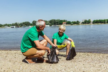 Nehir kıyısında çöpleri toplayan kıdemli gönüllüler. Ekoloji kavramı