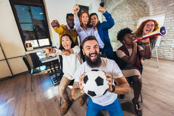 Happy casual business people or football fans watching soccer on tv and celebrating victory. Friendship, sports and entertainment concept.