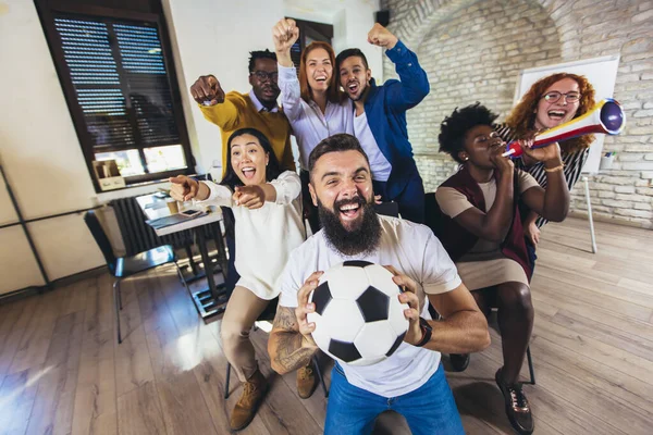 Happy casual business people or football fans watching soccer on tv and celebrating victory. Friendship, sports and entertainment concept.