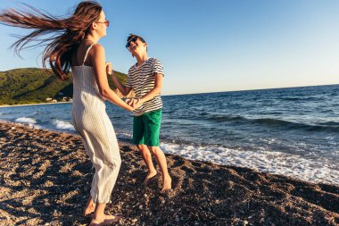 Erkek ve kız kardeş sahilde eğleniyorlar. Çocuklar sahilde dans ediyor.. 