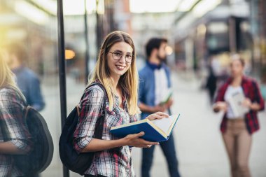 Mutlu üniversite öğrencisi üniversiteye gidiyor ve kameraya bakıyor..