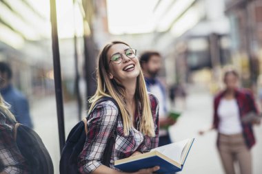 Happy university student going on a class at the university and looking at camera.