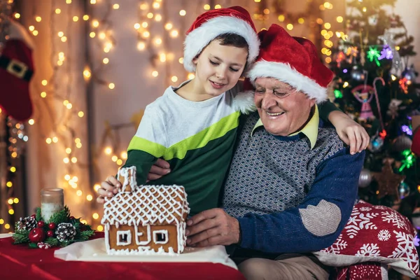 Grootvader Kleinzoon Zitten Stoel Met Peperkoekenhuis Tijdens Kerstvakantie — Stockfoto