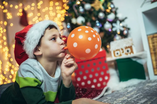 Happy Boy Lying Front Floor Christmas Tree Blowing Balloon Surrounded — 스톡 사진