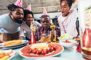 Multi-Generation african american family celebrating grandfathers birthday at home together