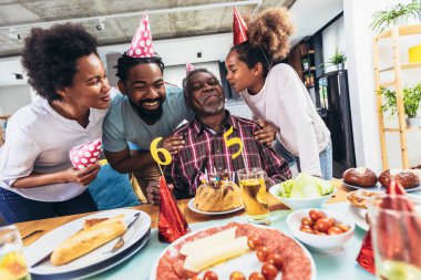 Multi-Generation african american family celebrating grandfathers birthday at home together