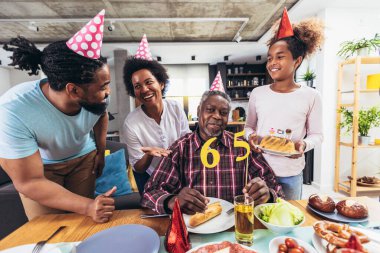 Multi-Generation african american family celebrating grandfathers birthday at home together