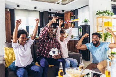Happy multi-generation family watching football match on television in living room at home