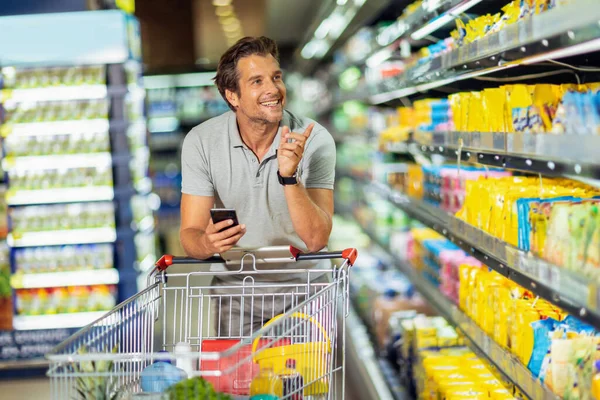 Handsome Man Using Smart Phone Smiling While Doing Shopping Supermarket — Foto Stock