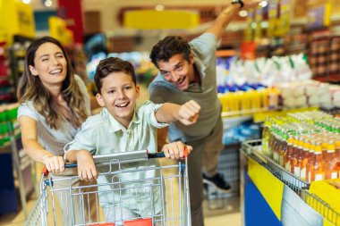 Çocuklu ve alışveriş arabalı mutlu bir aile marketten ya da marketten yiyecek alıyor.