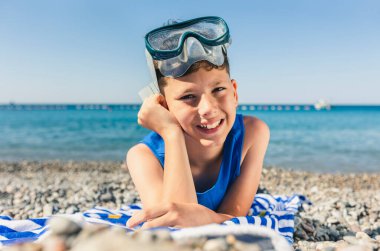 Little boy lying on beach and having fun.