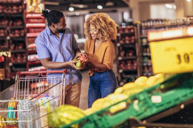 African american couple shopping for healthy fresh food at produce section of supermarket.