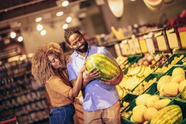 African american couple shopping for healthy fresh food at produce section of supermarket. clipart
