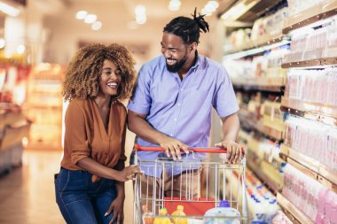 African American couple with trolley purchasing groceries at mall