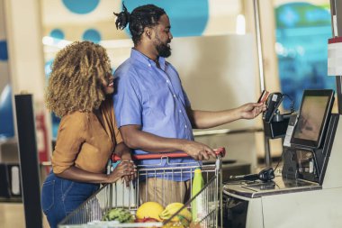 African American Couple with bank card buying food at grocery store or supermarket self-checkout
