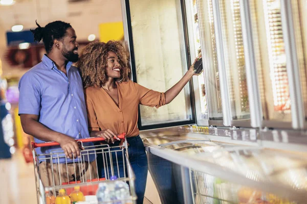 African American couple with trolley purchasing groceries at mall